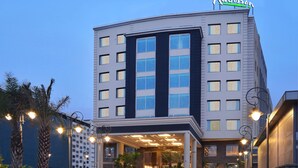 A modern hotel with a prominent entrance, multiple floors, and a well-lit facade. - Radisson Chandigarh Zirakpur (Dera Bassi)