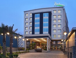 Un hotel moderno con una entrada destacada, varios pisos y una fachada bien iluminada.