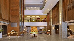 A spacious lobby with a central seating area, a reception desk, and a decorative floral arrangement. - Radisson Chandigarh Zirakpur (Dera Bassi)