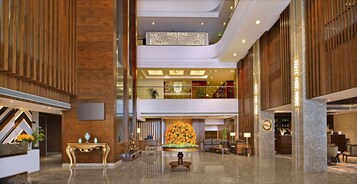 Un amplio vestíbulo con zona de estar central, mostrador de recepción y un arreglo floral decorativo.