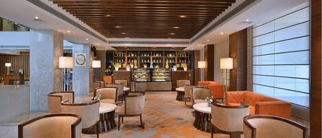 A hotel lobby with a reception desk, seating area, and a bar.