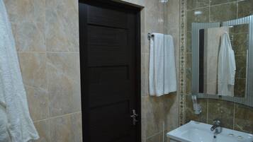 Un baño con una puerta de madera oscura, un lavamanos blanco y un espejo.