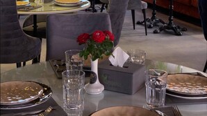 Un comedor con mesas dispuestas para dos, con vistas a la ciudad a través de grandes ventanales.