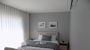 Un dormitorio moderno con una cama, mesitas de noche, una silla y dos cuadros enmarcados en la pared.