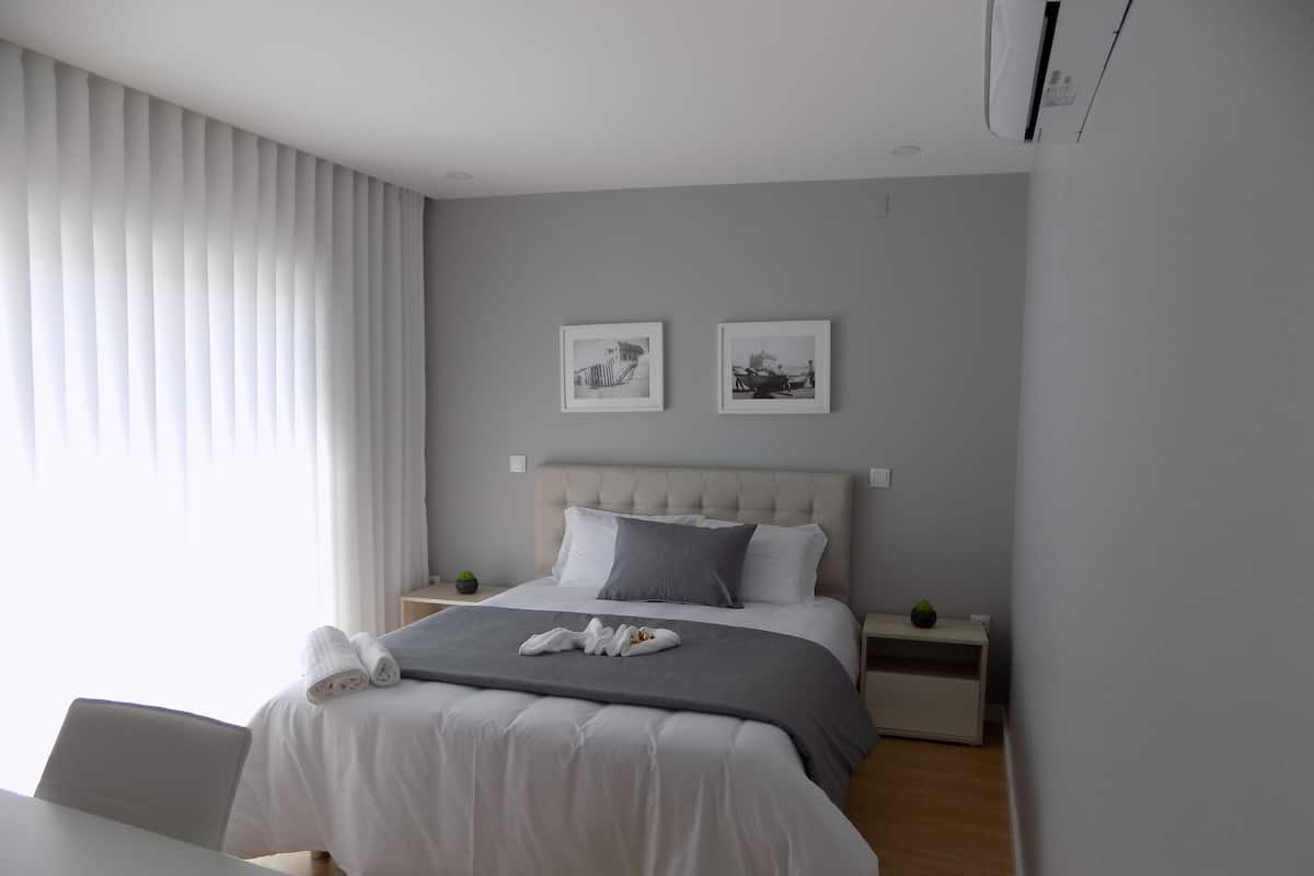 A modern bedroom with a bed, bedside tables, a chair, and two framed pictures on the wall.