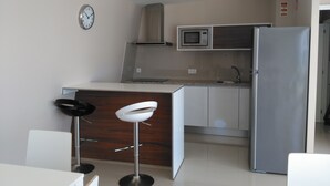 Una cocina moderna con microondas, refrigerador y un reloj en la pared.