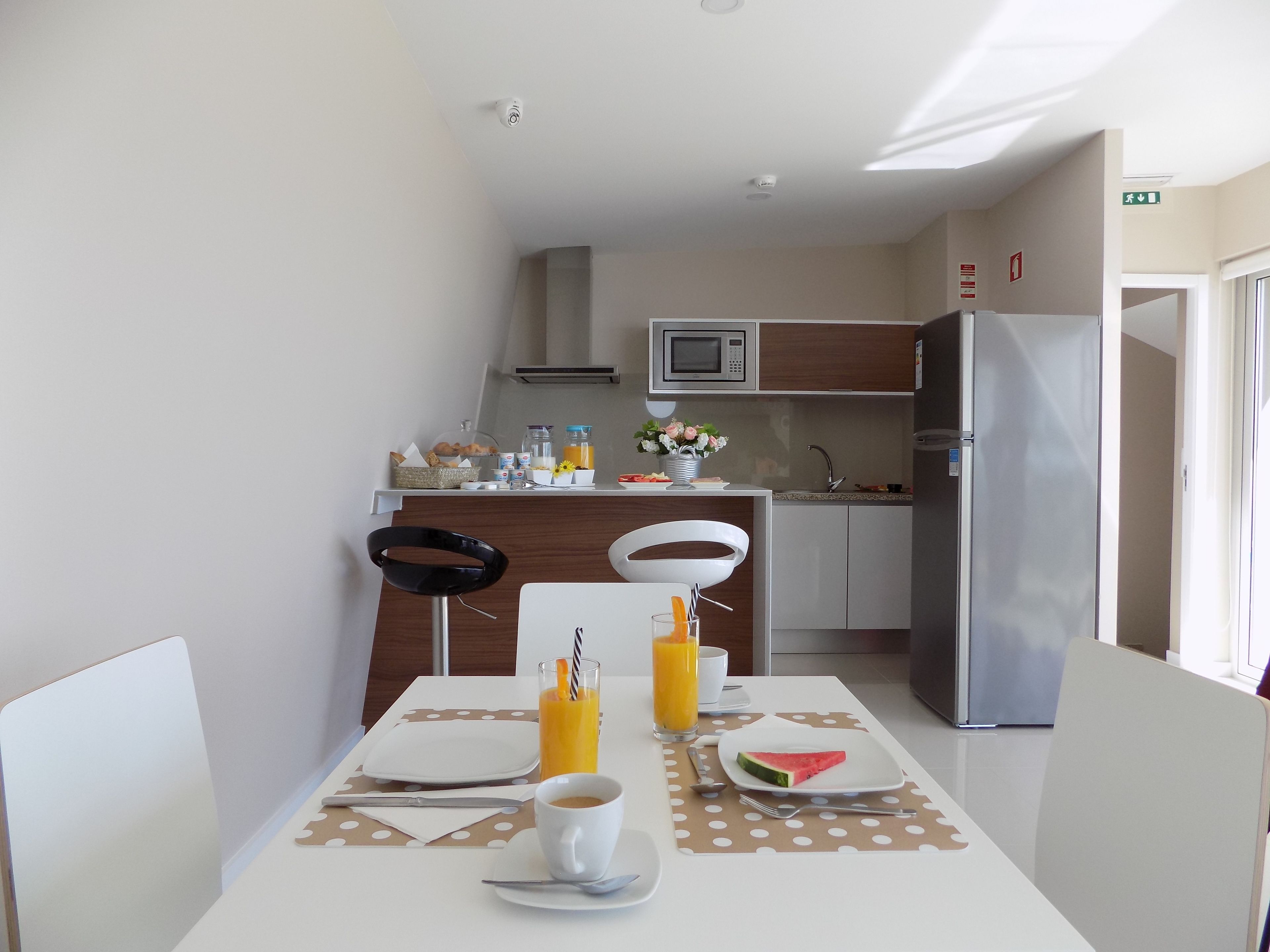 Uma sala de jantar com uma mesa posta para dois, um micro-ondas e uma geladeira ao fundo.
