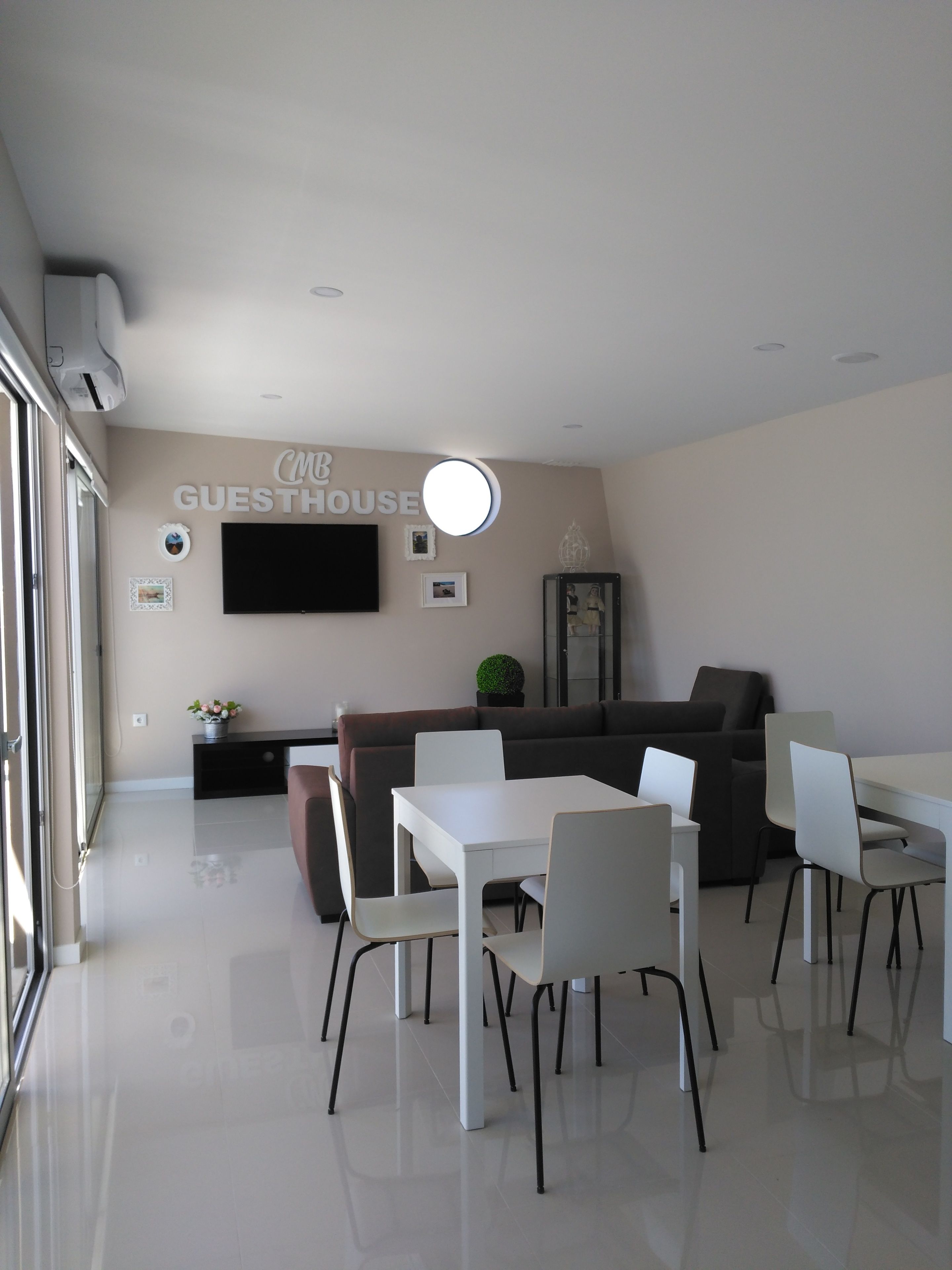 Interior moderno de una casa de huéspedes, con comedor, sofá y televisor de pantalla plana en la pared.