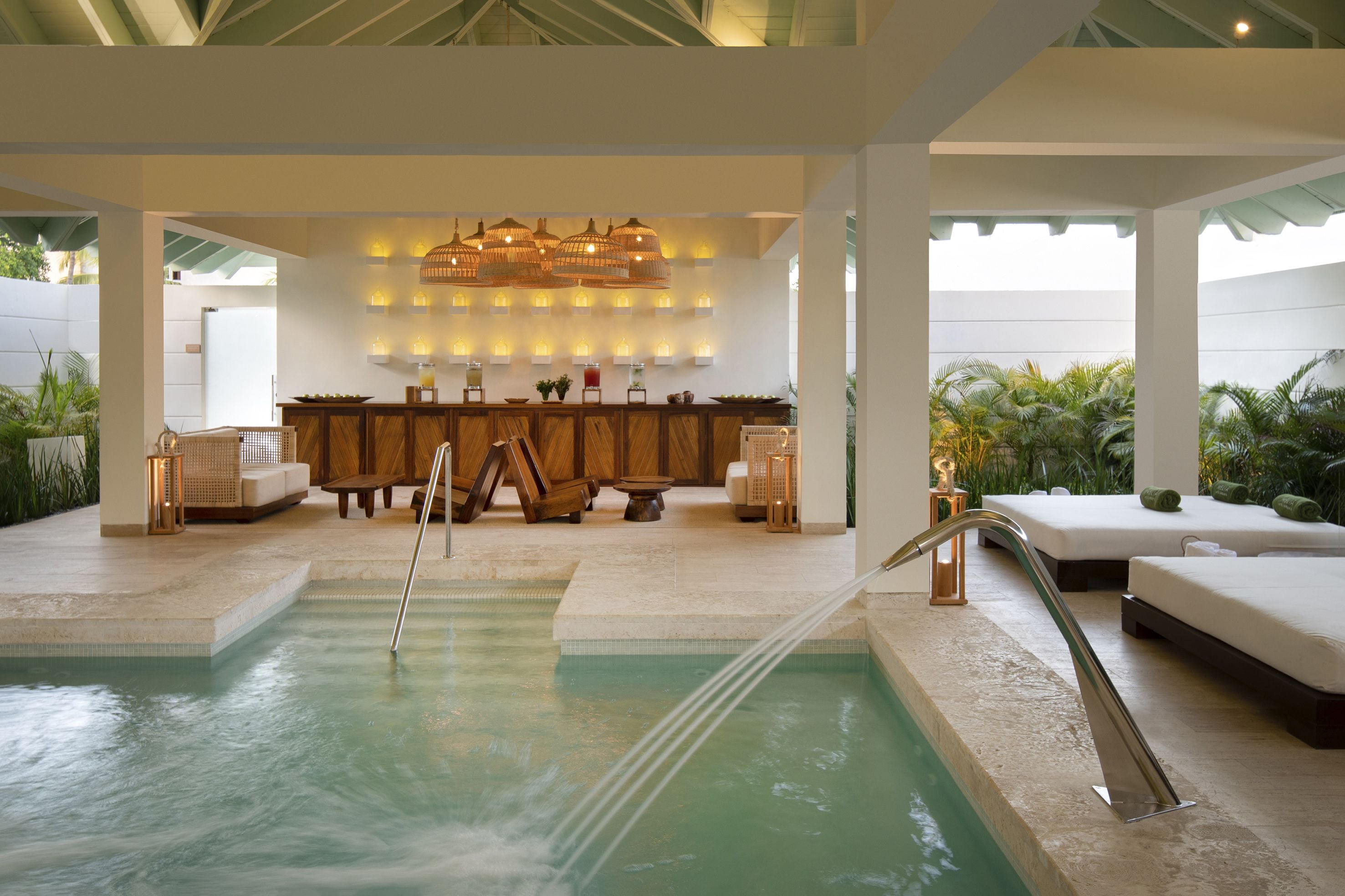 A pool area with a lounge, wooden furniture, and a bar with ambient lighting.