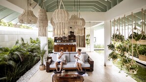 Un espace intérieur spacieux, aménagé avec un canapé, des plantes suspendues et un élément décoratif aquatique.