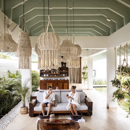 A spacious indoor area with a sofa, hanging plants, and a water feature.