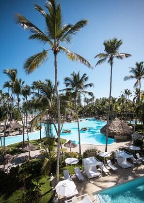 A resort with a large swimming pool surrounded by palm trees and lounge chairs. - Melia Punta Cana Beach Wellness Inclusive - Adults only - All inclusive (Punta Cana)