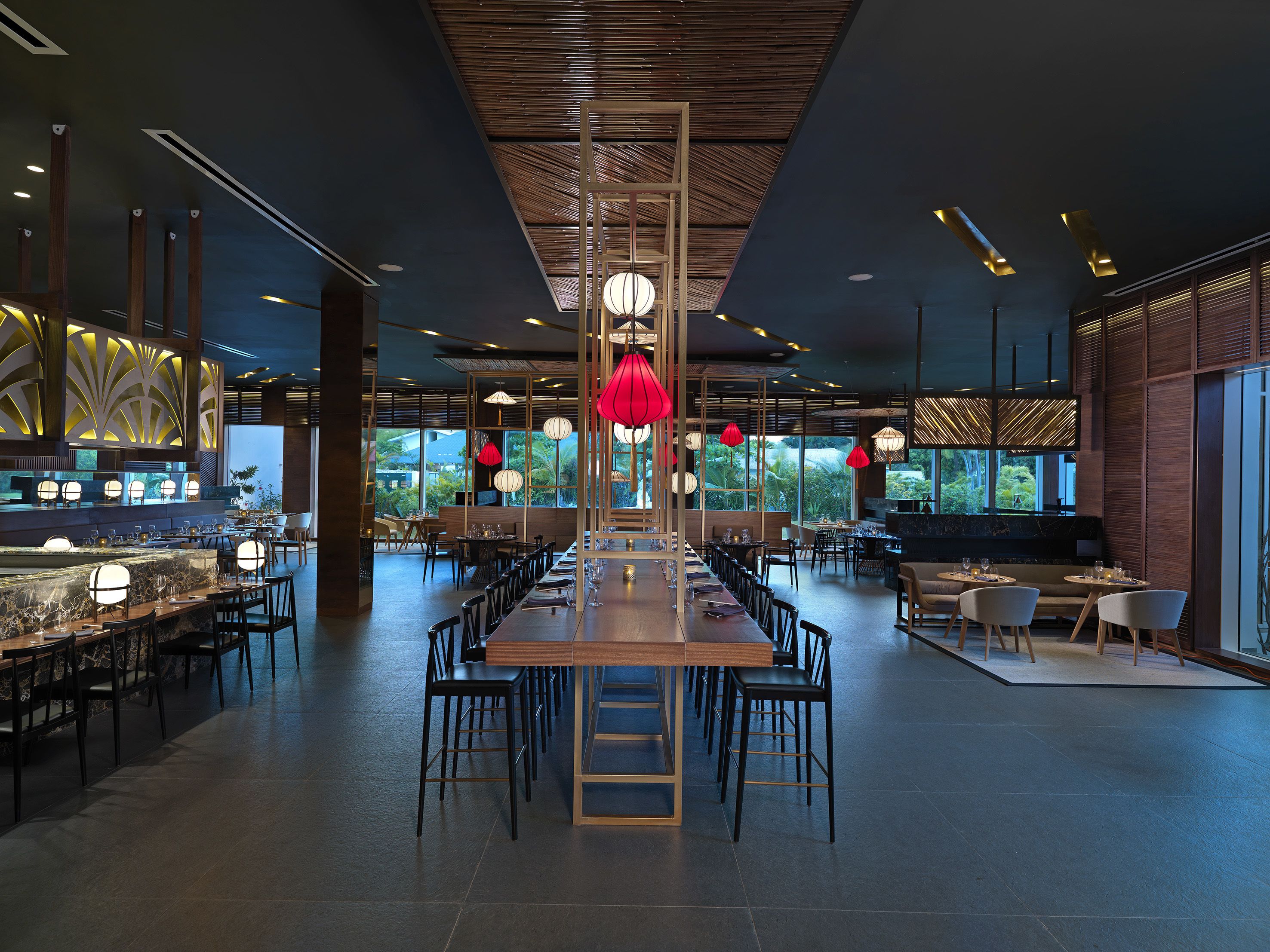 A spacious restaurant with high ceilings, modern lighting fixtures, and a view of the outdoors.