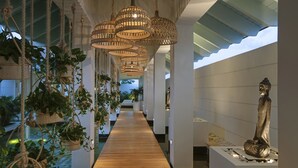 Un couloir orné de lampes en osier suspendues, doté d’un plancher en bois et orné d’une statue sur le côté droit.