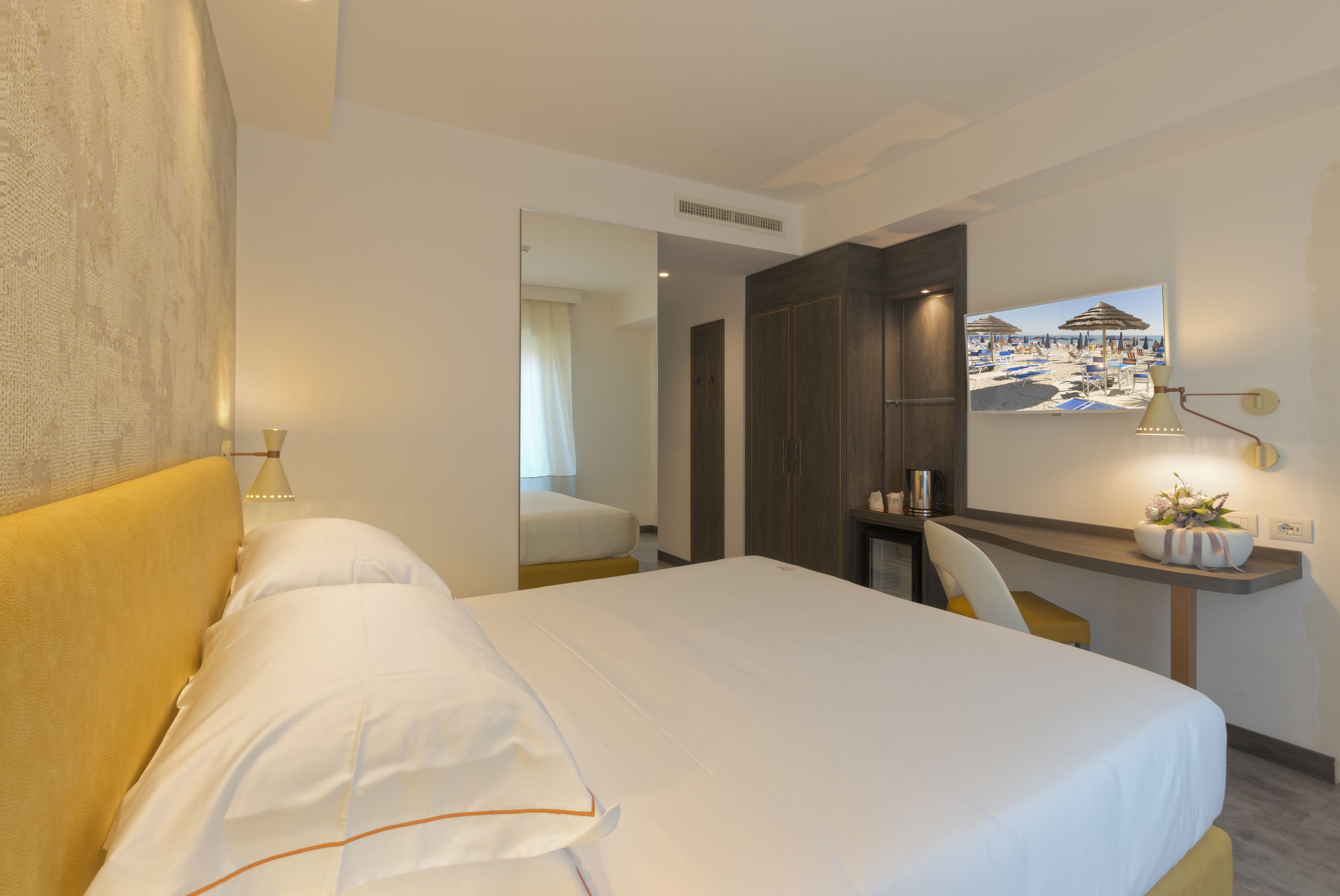 Une chambre d’hôtel équipée d’un lit, d’un bureau, d’une chaise et d’une grande fenêtre donnant sur la plage.