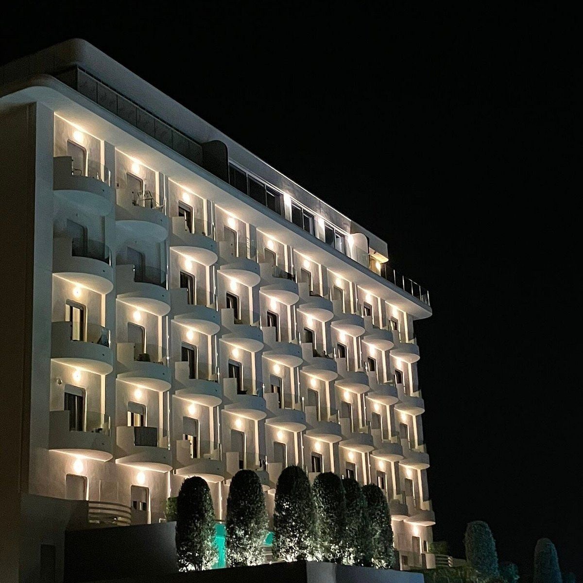 Un hotel de varios pisos con balcones y ventanas iluminadas durante la noche.