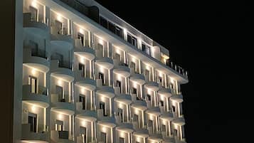 Un hotel de varios pisos con balcones y ventanas iluminadas durante la noche.
