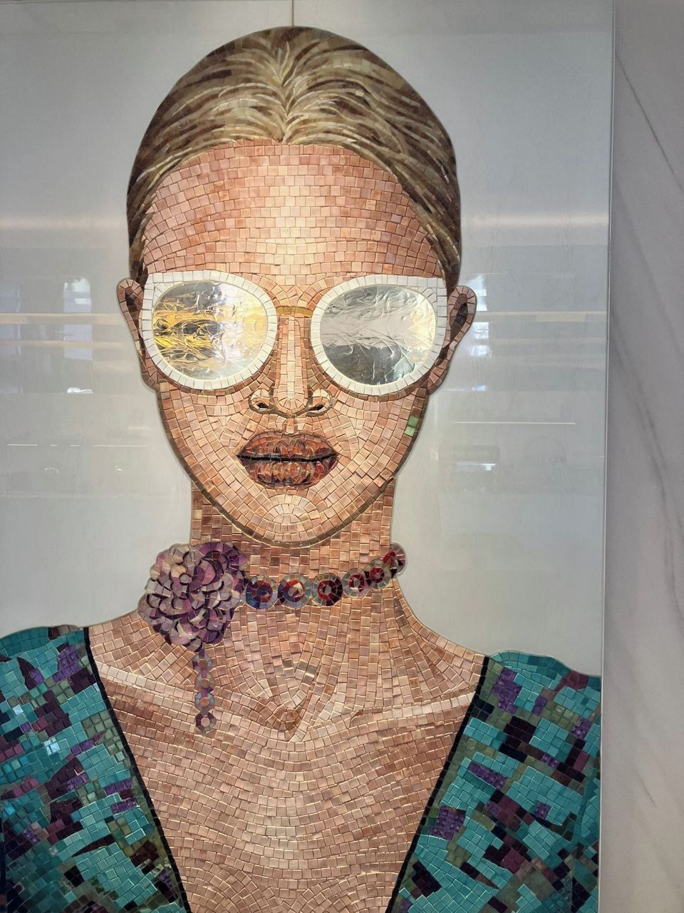 Une œuvre d'art en mosaïque représentant une personne portant un vêtement à motifs et un collier.