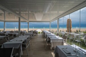 Un restaurante con mesas dispuestas para comer, con vistas a una playa.