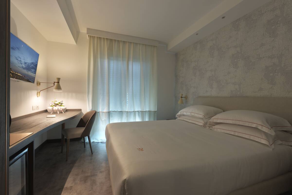 A modern hotel room with a large bed, a desk, and a chair.