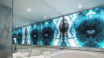 Un baño moderno con un espejo grande, una bañera y una pared con un diseño abstracto en azul.