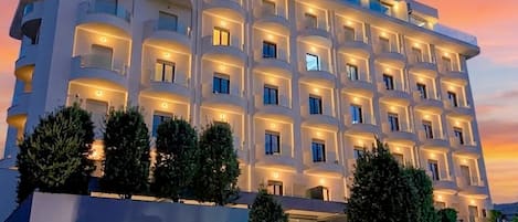 A multi-story hotel with a modern facade, illuminated windows, and a landscaped entrance.