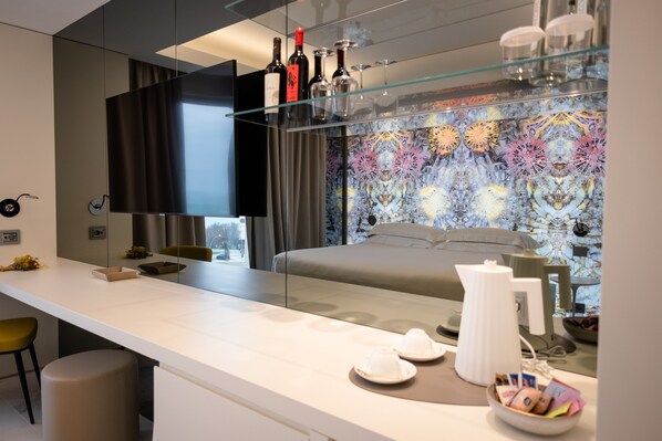 A modern hotel room with a large bed, a glass coffee table, and a minibar. - Ghibli Boutique Hotel Civitanova Marche (Civitanova Marche)