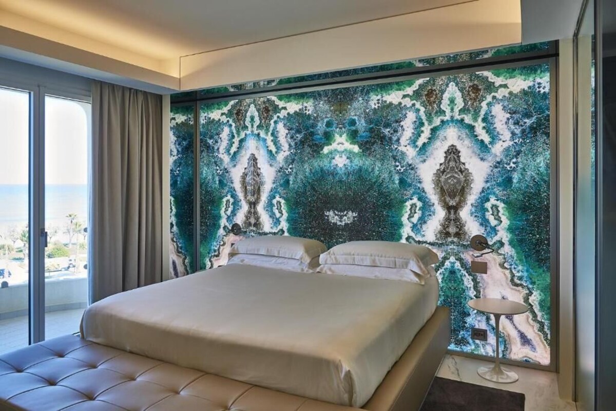 Une chambre d’hôtel avec un grand lit, une vue sur la mer et un mur décoratif.