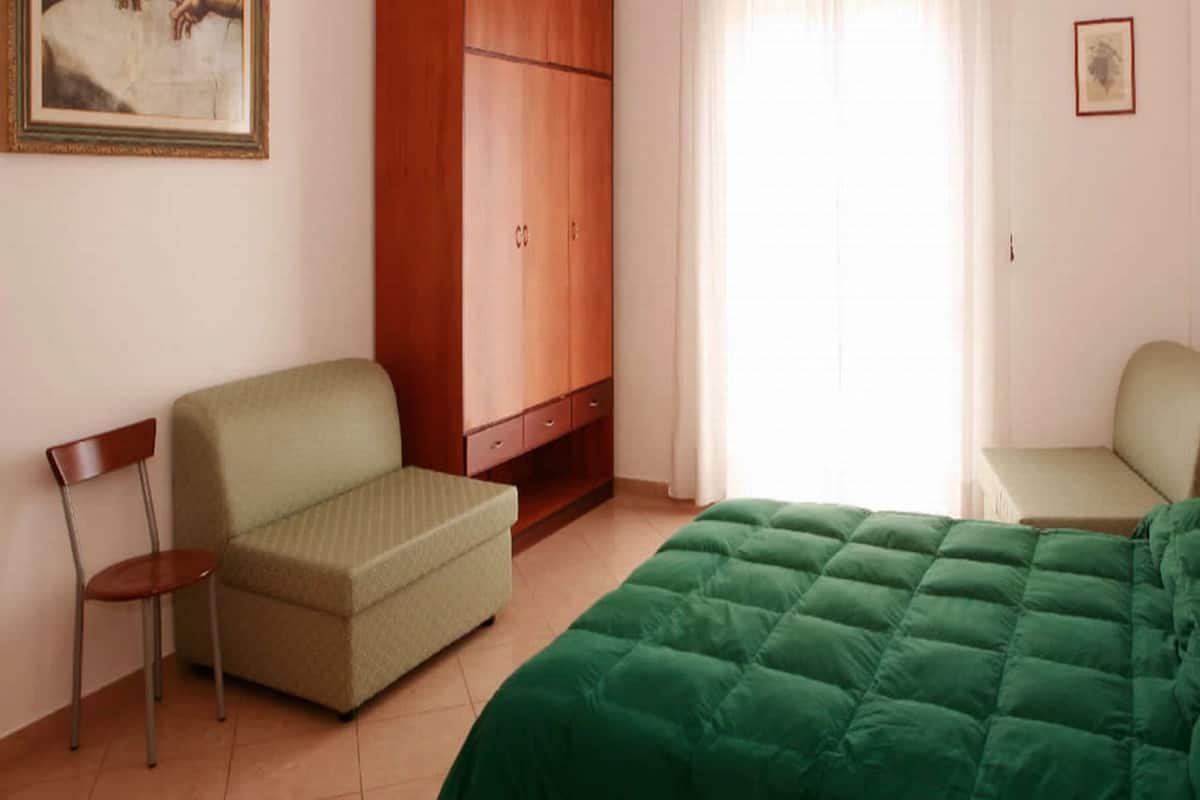 Une pièce comprenant un lit, un canapé, une chaise, une armoire et un tableau accroché au mur.