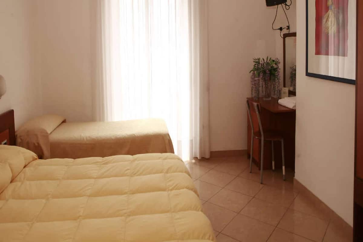 Une chambre d’hôtel avec deux lits, un bureau et une chaise.