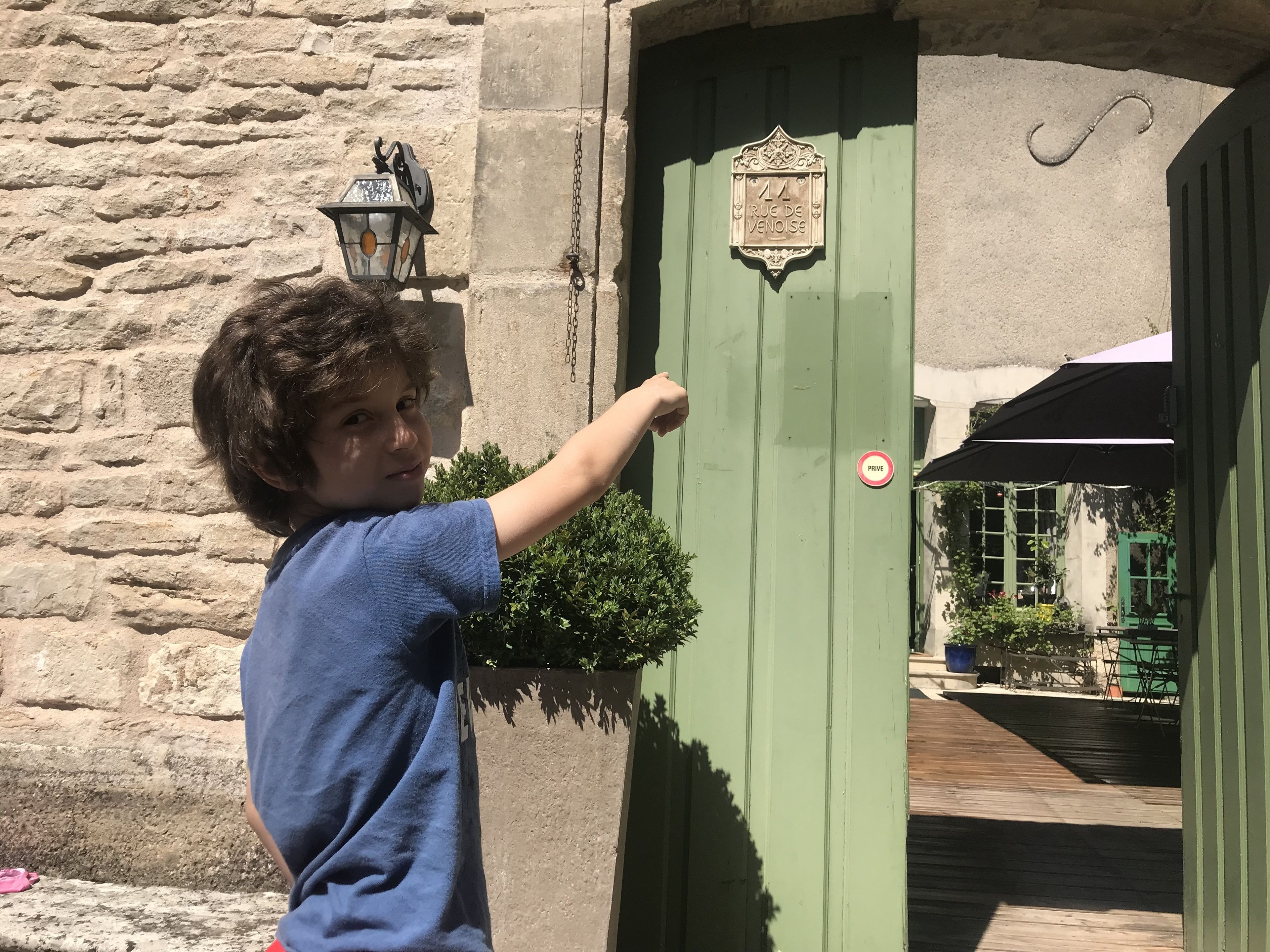 Un enfant ouvre une porte verte sur laquelle on peut lire l’inscription « Rue de Venoise ».