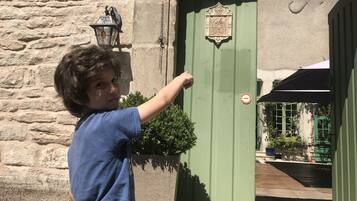 Un enfant ouvre une porte verte sur laquelle on peut lire l’inscription « Rue de Venoise ».
