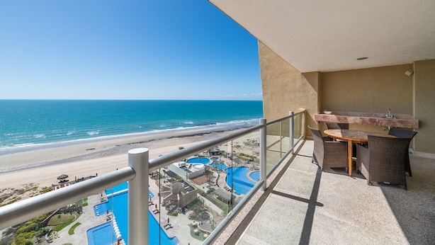 A balcony with a view of the beach and a pool area. - Encanto Living 1101 -2BR by Kivoya (Puerto Peñasco)