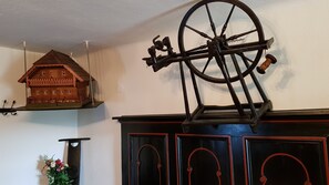 A wooden house model on a shelf, a large mechanical wheel, and a fireplace with decorative doors. - Roseggerhof (Sankt Kathrein am Hauenstein)