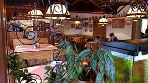 Un restaurante con mobiliario de madera, lámparas colgantes y plantas en macetas.