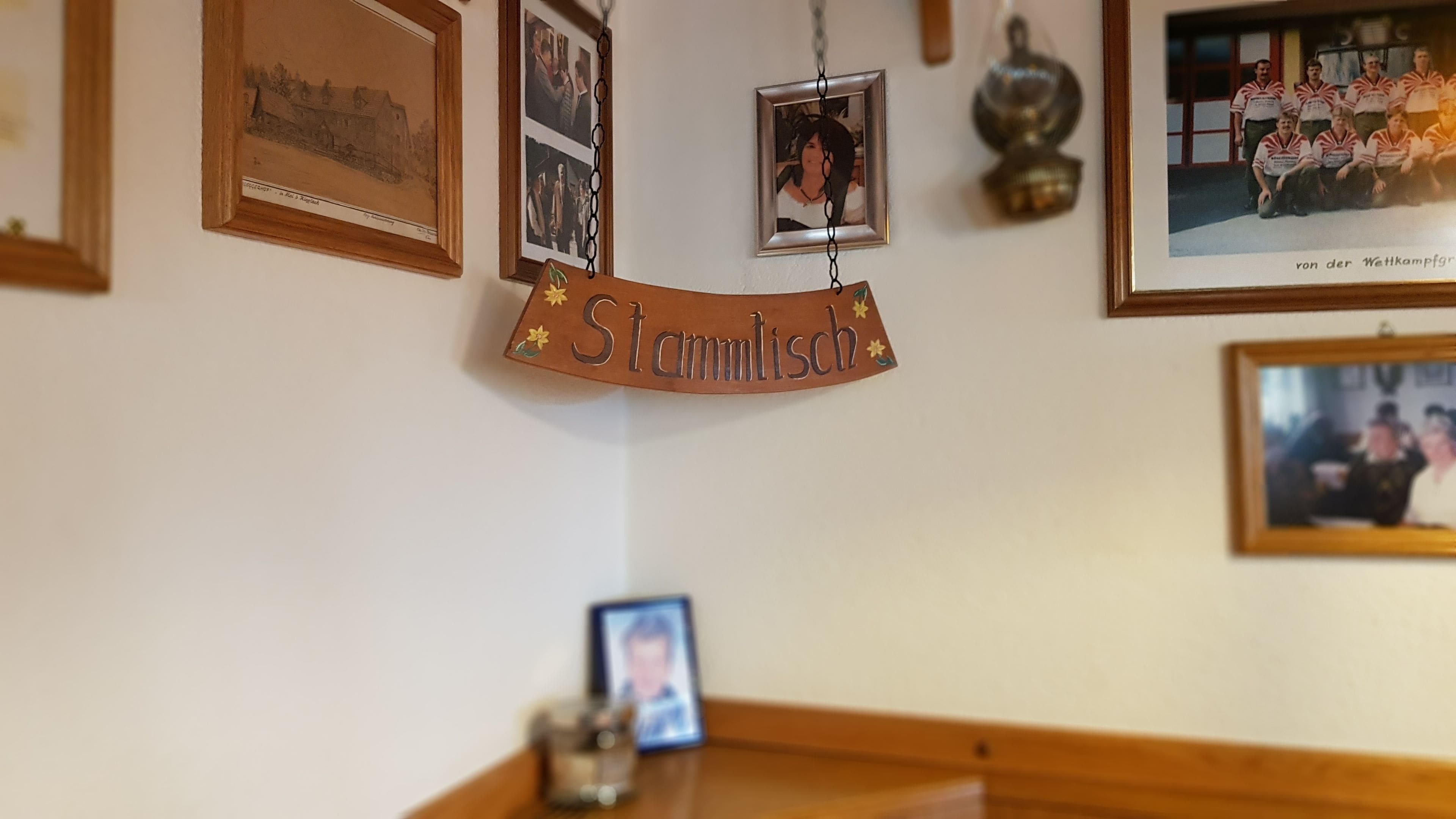 Una pared con fotografías enmarcadas y un cartel que dice "Stammisch".