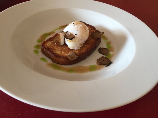 A plate with toast topped with a poached egg and mushrooms, served on a white plate. - Ramsey House (Haverfordwest)