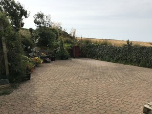 Un espacio exterior empedrado con plantas en macetas y vista a un campo.