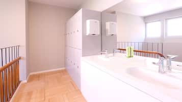 A modern bathroom with two sinks, a large mirror, and a wooden staircase.