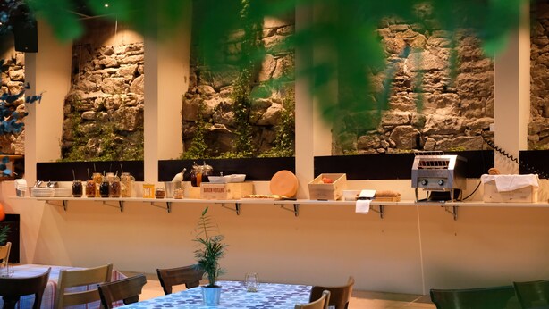 A restaurant with stone walls, a bar area, and tables with chairs. - Barabas - Hostel (Lucerne)