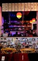 Un bar japonés tradicional con letreros de madera, faroles colgantes y una pared de grabados tradicionales ukiyo-e.