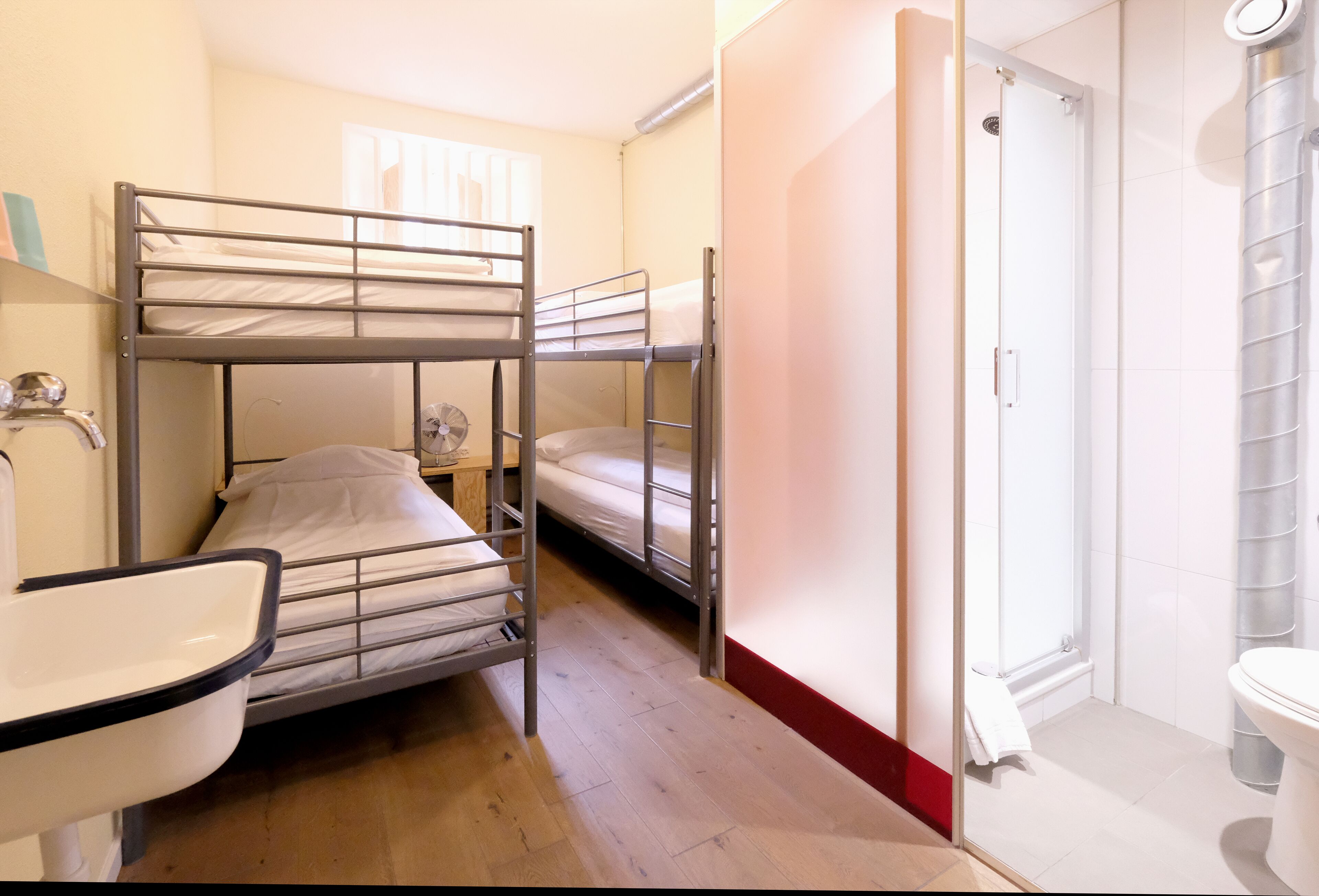 Une chambre de dortoir équipée de lits superposés, d’un lavabo, d’un miroir et d’un espace douche.