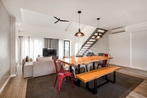 A modern living room with a wooden dining table, red chairs, a sofa, and a TV. - YOUROPO - Central (Porto)