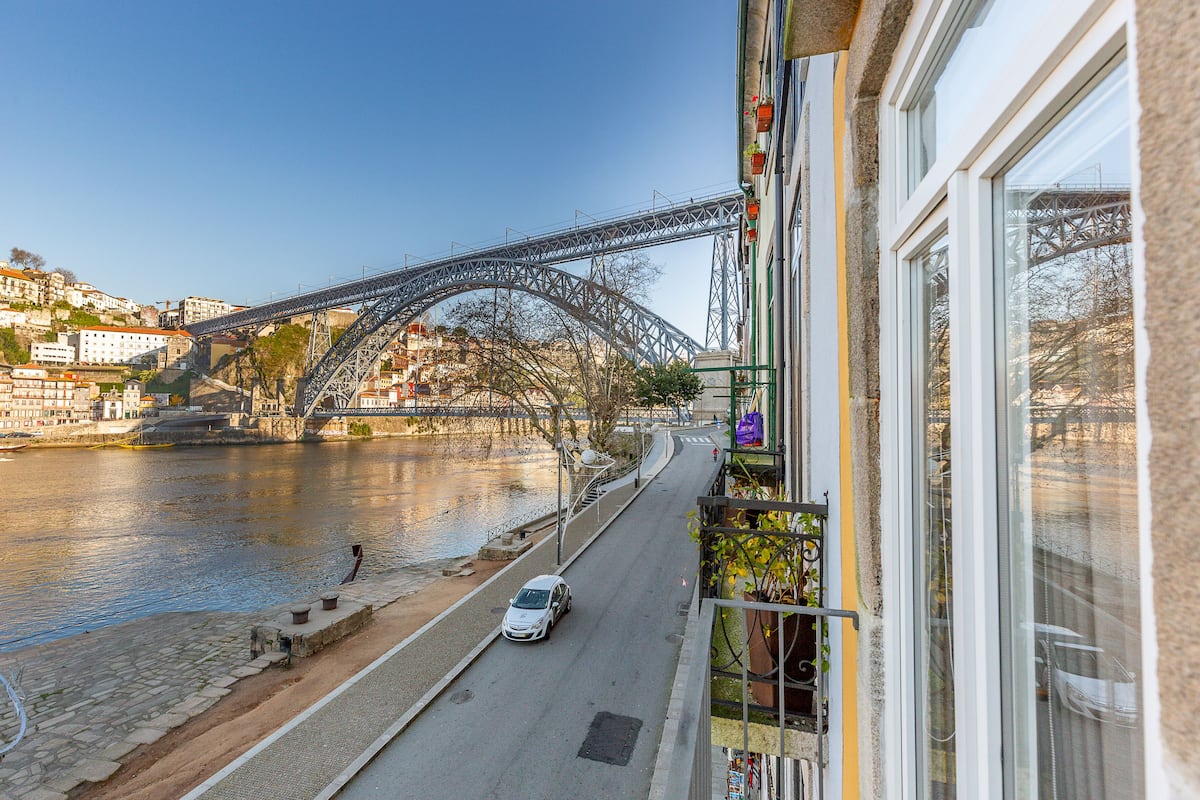 Une rivière avec un pont, une rue avec une voiture et des immeubles avec des balcons.