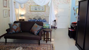 A bedroom with a canopy bed, a sofa, a small table, and a wardrobe. - The London Tearoom (Chiang Mai)
