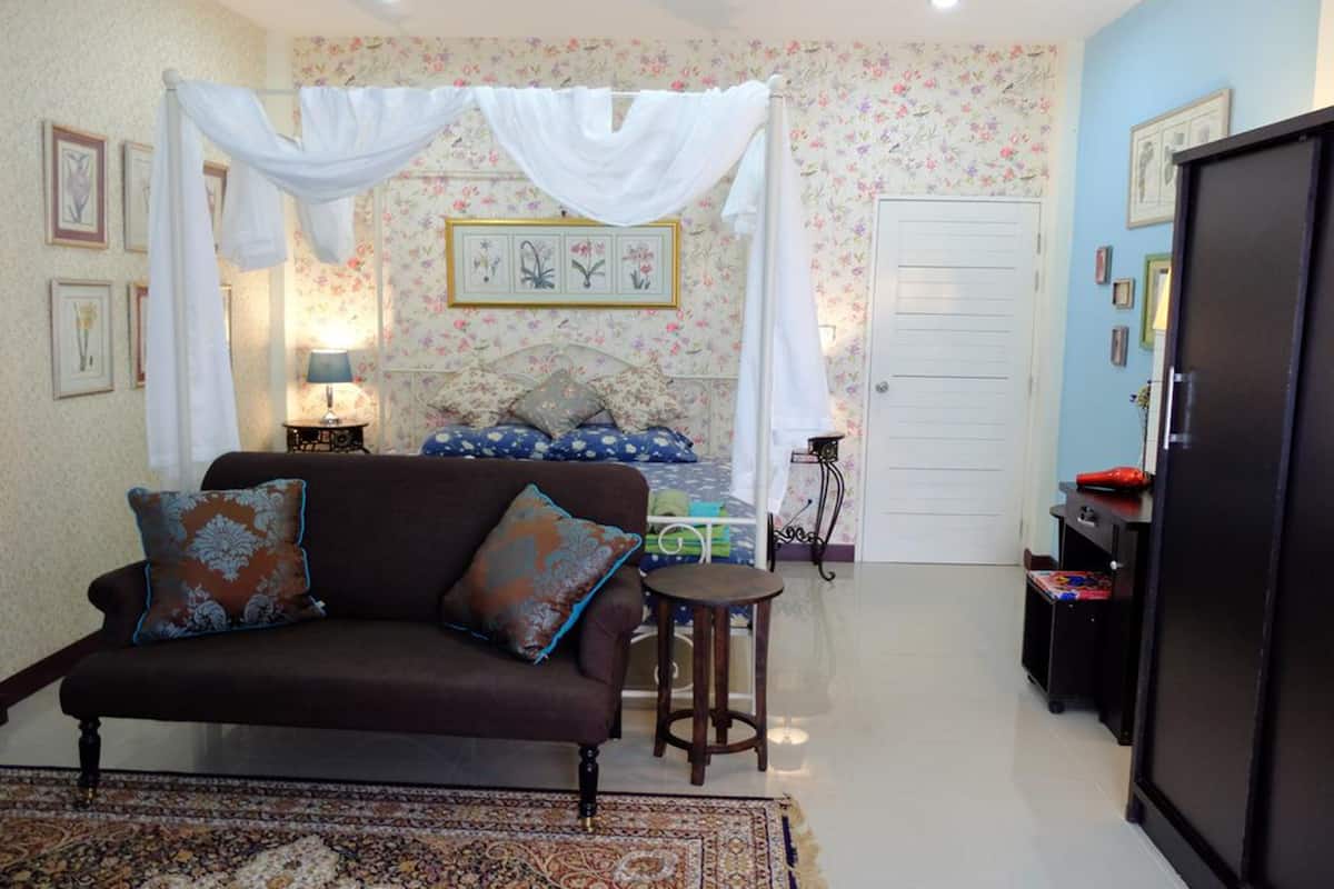 A bedroom with a canopy bed, a sofa, a small table, and a wardrobe.