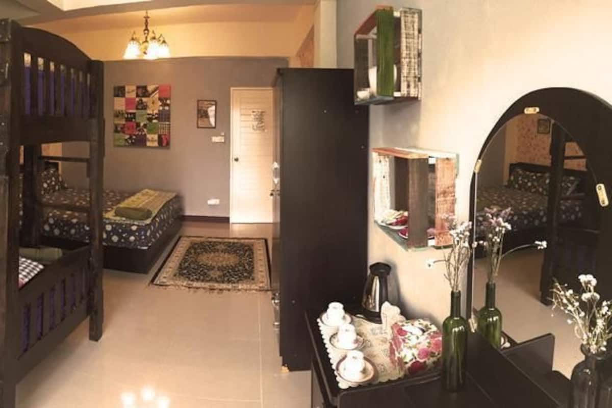 A room with bunk beds, a chair, a desk, and a mirror.