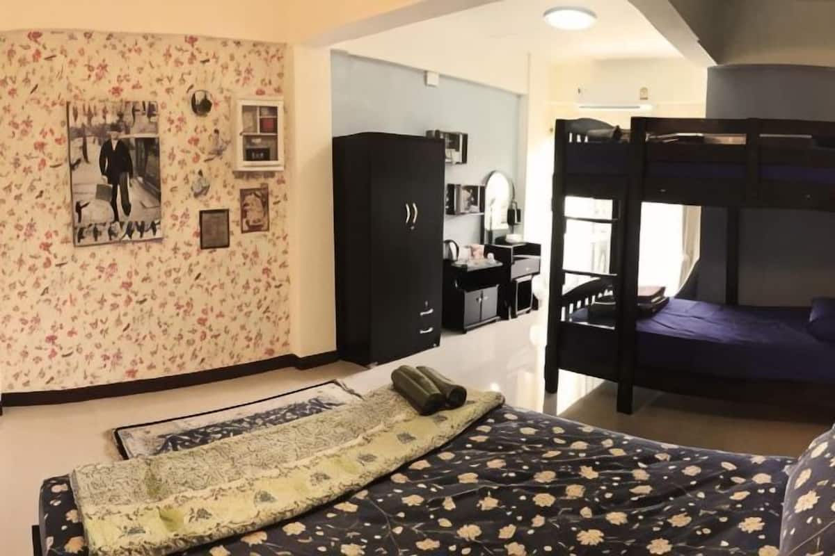 A bedroom with a bunk bed, a desk with a chair, a wardrobe, and a patterned wall.