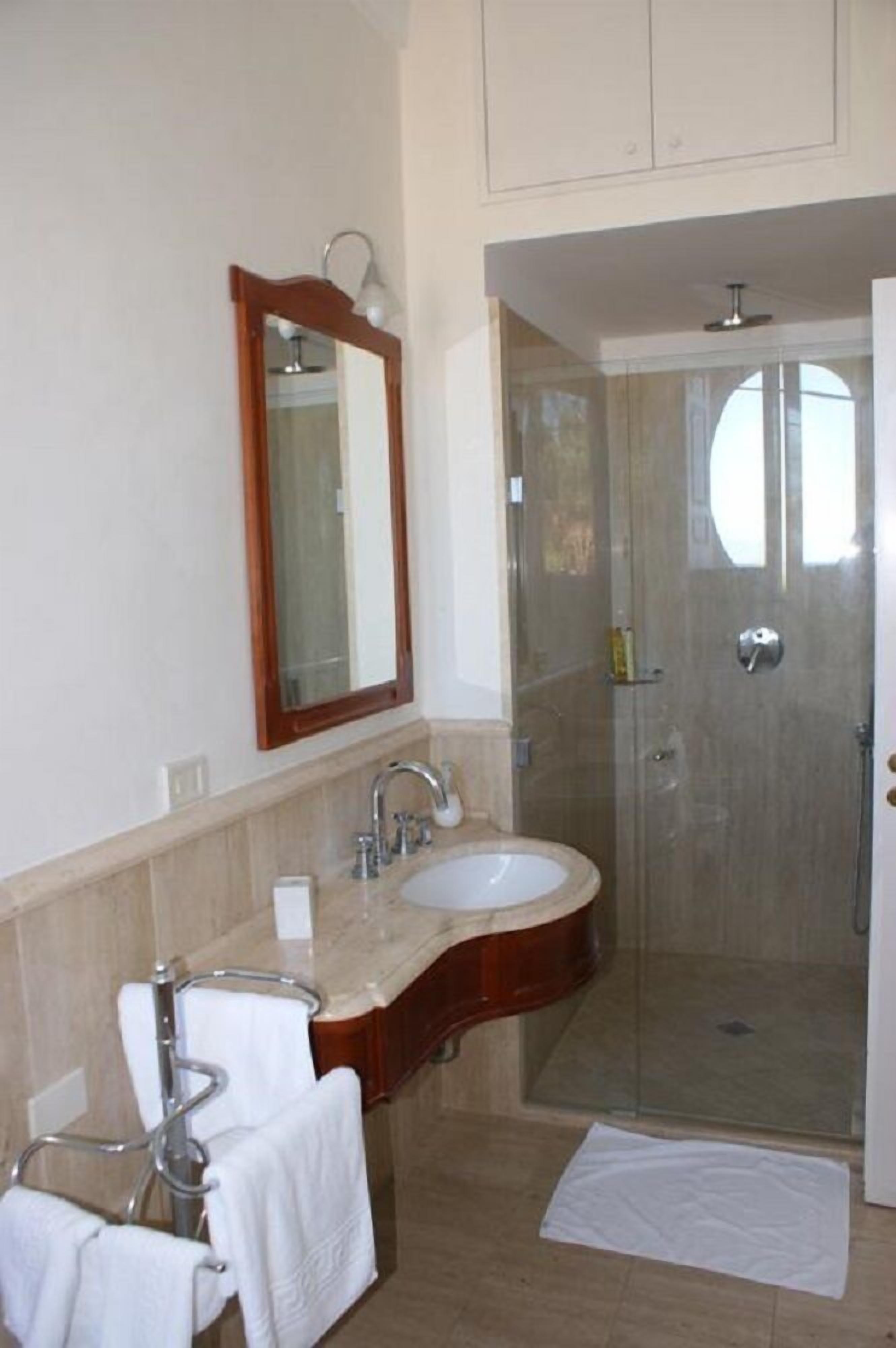 A bathroom with two sinks, a mirror, a shower, and a towel rack.