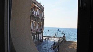 A view through a circular window of a coastal promenade with buildings and a beach. - Palazzetto Florio (Castellabate)